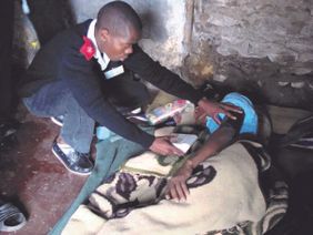 A care team worker tends to a woman in her home.