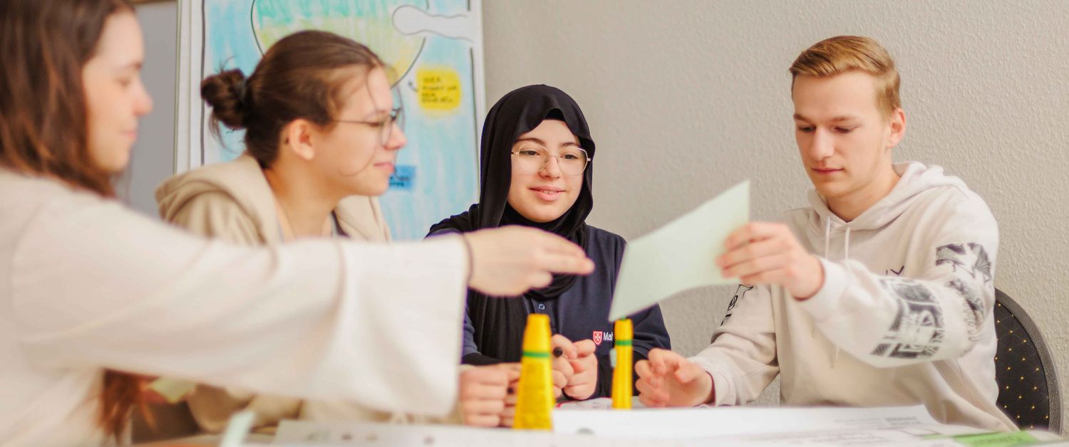 Junge Menschen basteln am Tisch