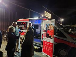 Interessierte informieren sich neben einem Roll-Up und vor dem neuen Herzenswunsch-Krankenwagen über den Dienst