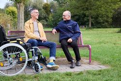 Zwei Männer unterhalten sich, einer hat einen Rollstuhl dabei