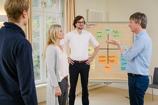 4 Personen stehend vor Moderationstafel