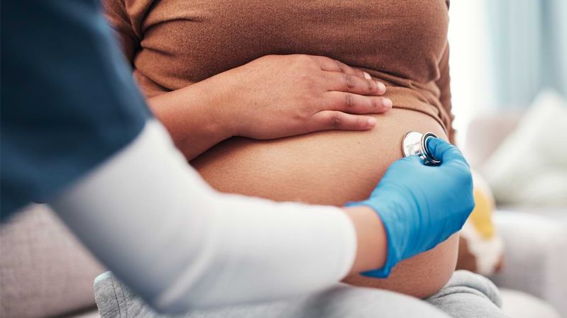 Der Bauch einer schwangeren Frau wird mittels eines Stethoskops untersucht.