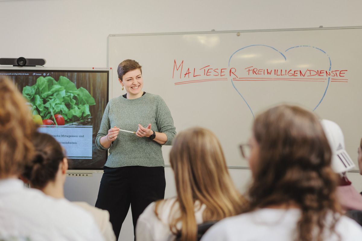 Seminarleiterin spricht vorne zu ihr gegenüber sitzenden menschen