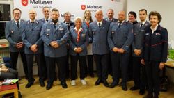 Viele Menschen in Malteser Dienstbekleidung stehen aufgereiht da.