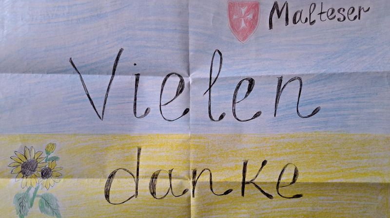 Ein Bild mit der Aufschrift „Vielen danke“ zeigt eine Sonnenblume, das Logo der Malteser und die Flagge der Ukraine.