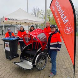 Frauen des Malteser Hilfsdienstes stehen neben eine Fahrradrikscha