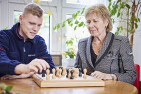 Ein junger Malteser spielt mit einer älteren Dame Schach