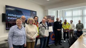 12 Verantwortliche für den Katastrophenschutz für die Stadt Osnabrück posieren vor einem Smartboard anlässlich der Unterzeichnung der Sicherstellungsvereinbarung.