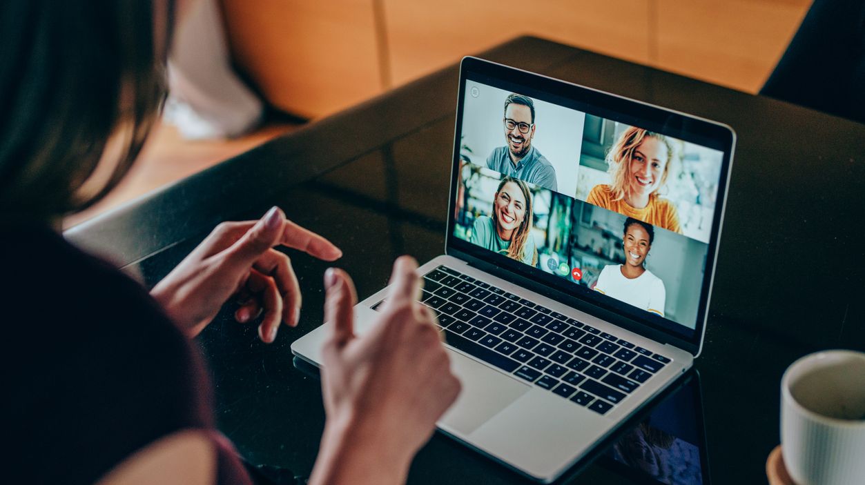 Junge Frau sitzt vor einem Laptop und nimmt an einer Videokonferenz teil.