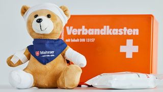 Erste Hilfe Verbandskasten mit Teddy, der verbunden und gepflastert ist