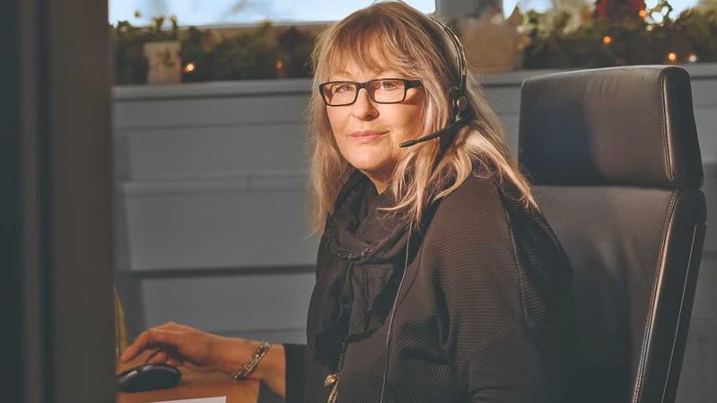 Eine Frau mit Headset an einem Schreibtisch; dahinter Weihnachtsdekoration.