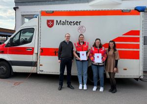 Die ausgezeichneten Malteser Helferinnen mit zwei anderen Maltesern vor einem Krankentransportwagen. 