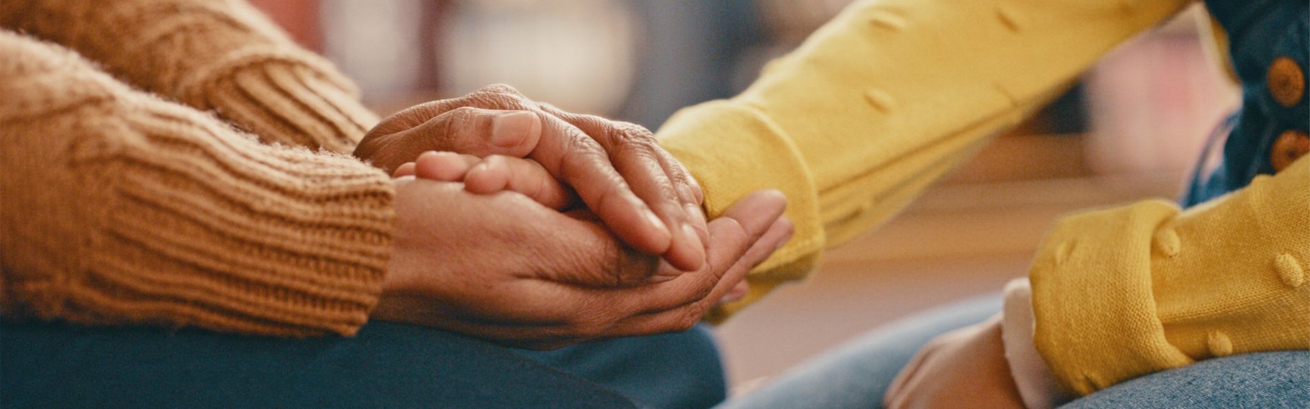 Die beiden Hände einer Person halten unterstützend die Hand einer anderen Person.