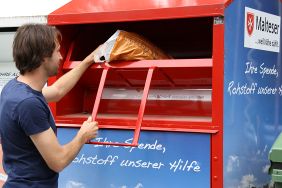 Mann wirft einen Sack in einen Malteser Altkleider Container