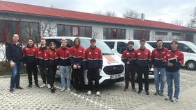 Viele Personen in Malteser Kleidung stehen vor einigen Malteser Fahrzeugen.