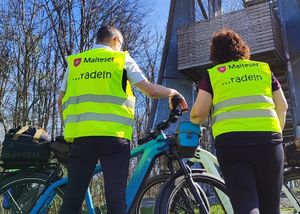 Zwei Fahrradfahrer von hinten mit ihren Bike. Sie tragen eine gelbe Warnweste.
