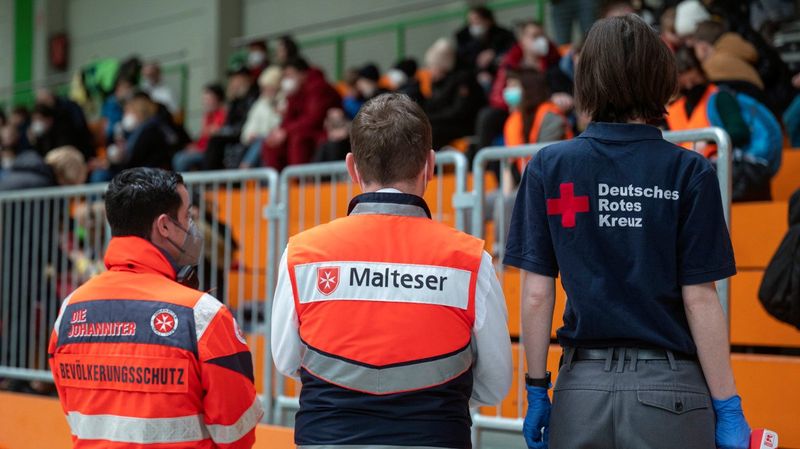 Drei Angehörige von Hilfsorganisationen mit dem Rücken zur Kamera. 