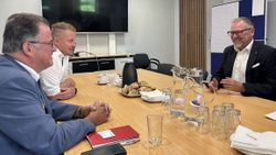 Drei Männer sitzen gemeinsam an einem Besprechungstisch