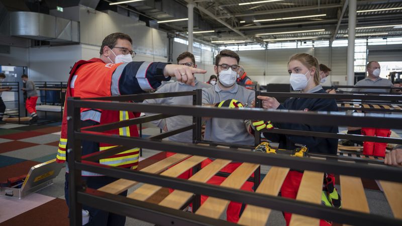 Menschen beim Aufbau einer Unterkunft für Geflüchtete in einer großen Halle