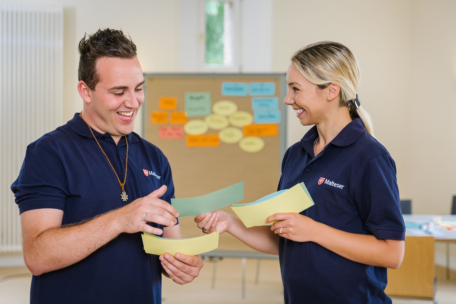 Malteser tauschen sich mit Zetteln in der Hand aus