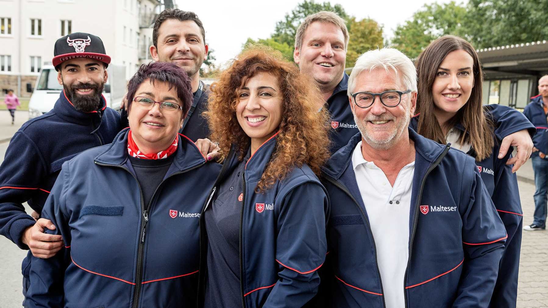 Diverse Gruppe aus Frauen und Männern in Uniform der Malteser