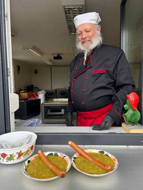Ein Ehrenamtlicher gibt Erbsensuppe aus 