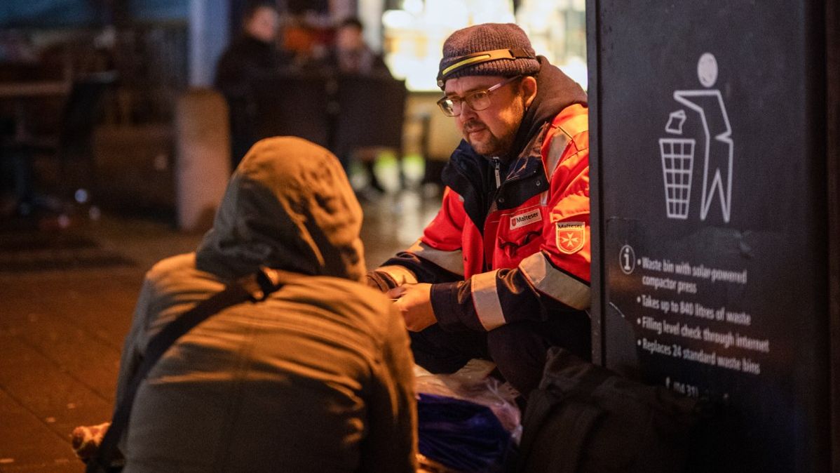 Zwei Männer knien auf einem Bürgersteig