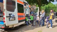 Kinder stehen in einer Schlange vor einem Rettungswagen.