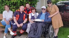 Mehrere Menschen sitzen auf einer Bank.