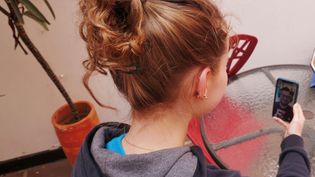 Ein Mädchen sitzt am Tisch und hält ein Smartphone in der Hand. Sie telefoniert per Video mit einem jungen Mann, der gerade Deutsch lernt.