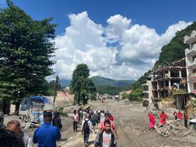 Menschen gehen durch eine von Schlamm und Geröll verwüstete Straße in Nepal. Foto: Prabin Shrestha/KOSHISH