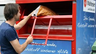 Mann wirft Altkleidung in einen Container der Malteser