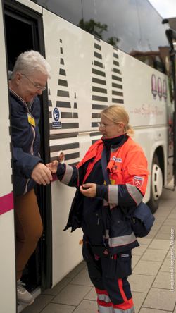 Eine Malteser Helferin begleitet den Ausstieg einer Pilgerin aus dem Bus bei der Ankunft in Kevelaer