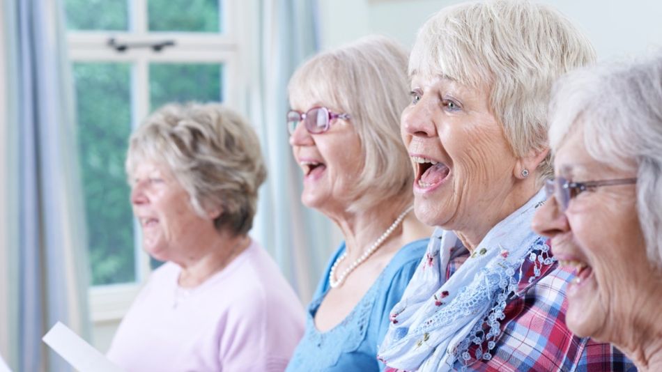 Vier ältere Frauen mit Notenblättern in der Hand singen