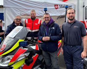 Drei Malteser und der Innenminister des Saarlandes stehen vor einem Motorrad der Malteser Motorrad Staffel.