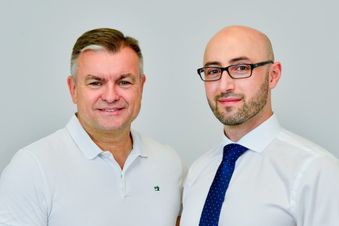 Zwei Männer stehen vor einer Wand.