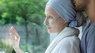 Junge kranke Frau schaut aus dem Fenster