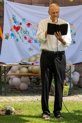 Stephan Skroch stehend auf einer Wiese mit Buch (Foto: Malteser Mainz)