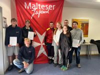 Acht Jugendliche stehen vor einem Malteser Jugend Banner und lächeln in die Kamera.