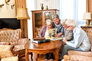 Vier Frauen sitzen auf dem Sofa und schauen sich gemeinsam ein Fotoalbum an