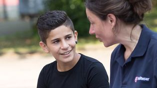 Eine junge Malteser Integrationslotsin unterhält sich mit einem Jungen.