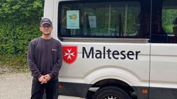 Ein Helfer im Bundesfreiwilligendienst steht vor einem Malteser Kleinbus.