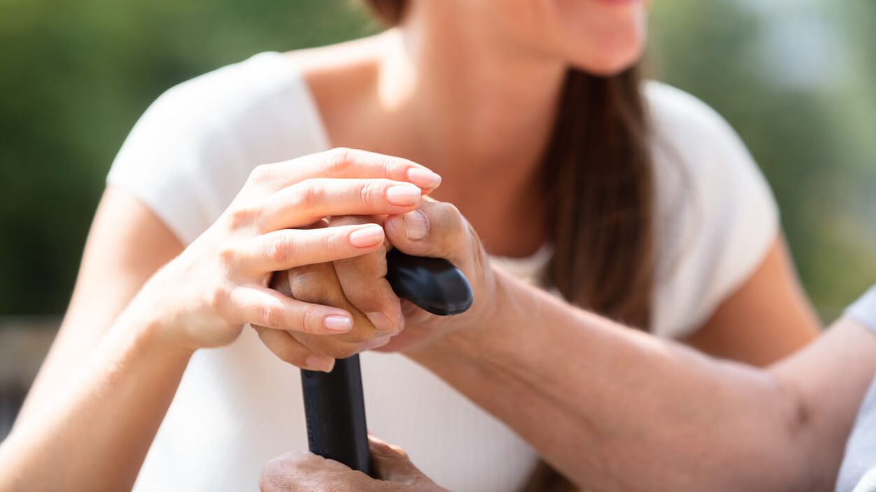 Junge Frau hält die Hände einer älteren Person