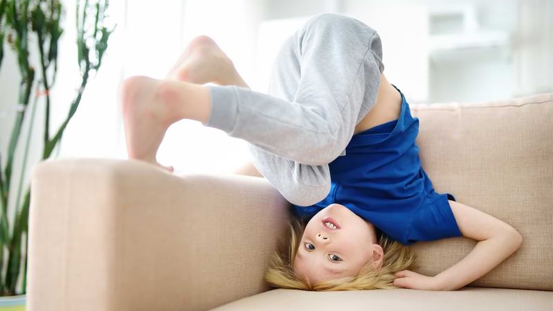 Ein kleiner Junge schlägt einen Purzelbaum auf einem Sofa.