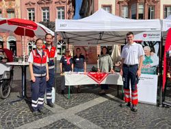 Auf dem Foto sind mehre Personen der Malteser zu erkennen an einem Informationsstand der Malteser. 