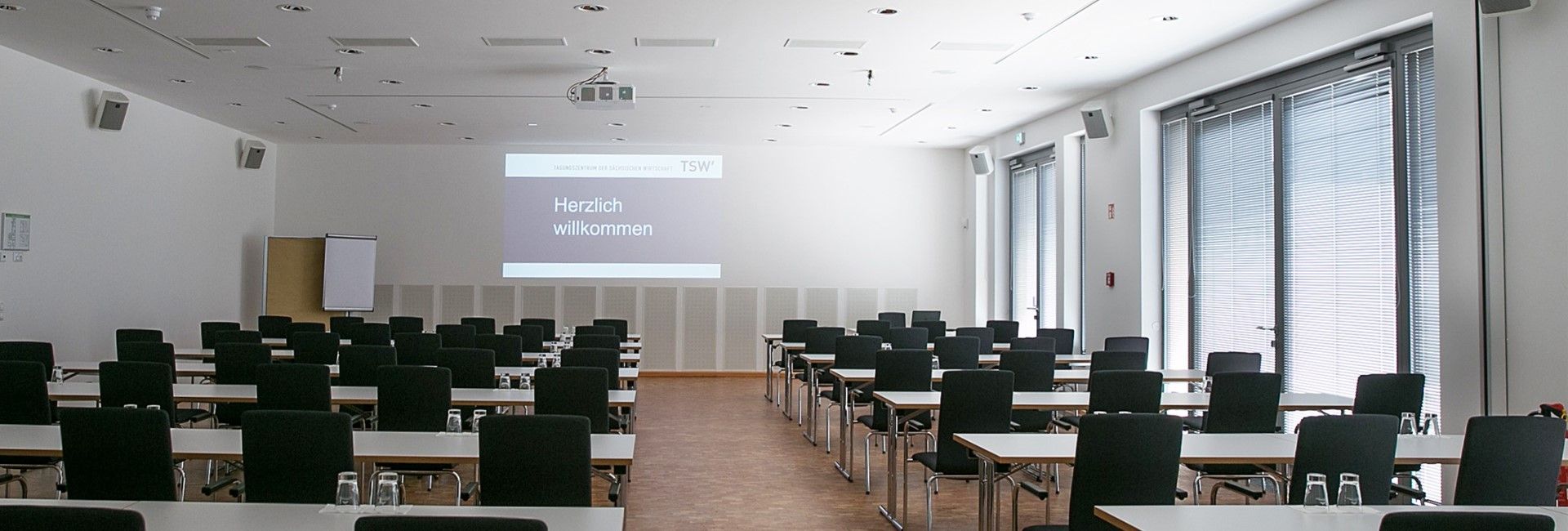 Heller Seminarraum im Tagungszentrum mit Tischen, Stühlen und Präsentationsfläche für Schulungen und Workshops.