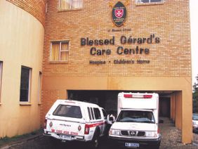 The Blessed Gérard Care Centre with two service vehicles parked outside.