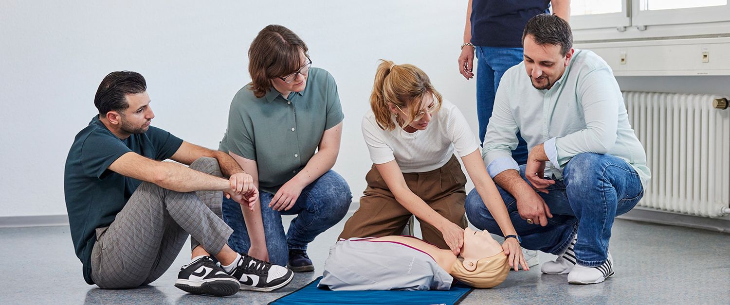 Beim Erste-Hilfe-Kurs der Malteser: Eine Gruppe übt an einer Puppe die Herzdruckmassage.