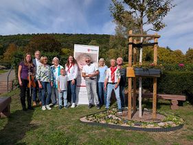 Familien, Ehrenamtliche und Unterstützende versammelten sich zur Gedenkfeier am Gedenkbaum für verstorbene Kinder auf dem Friedhof in Gelnhausen. (Foto: Malteser Kinderhospiz- und Familienbegleitdienst Main-Kinzig-Kreis)