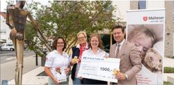 Spendenübergabe in Schlüchtern: Vier Personen präsentieren einen symbolischen Scheck über 1.000 Euro für den Malteser Hospizdienst vor einem Malteser-Banner. Foto: © Bensing & Reith